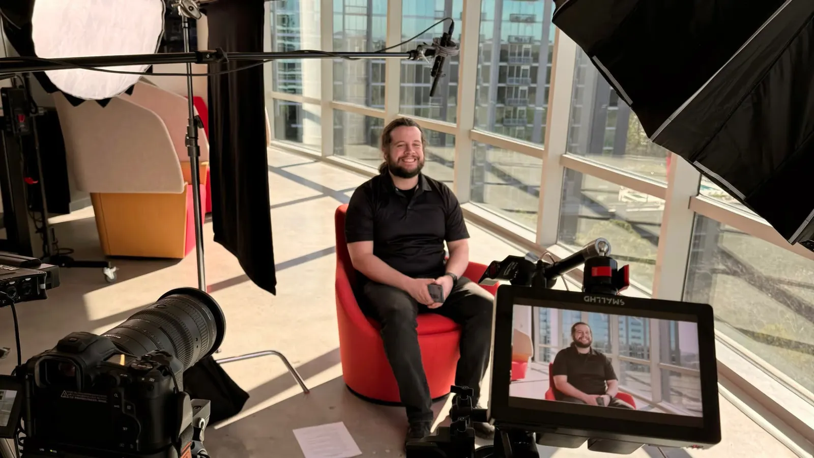 Interview setup with lights and monitor in a glass-walled office
